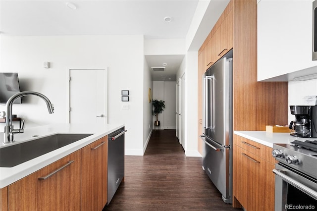 kitchen featuring brown cabinets, high end appliances, light countertops, a sink, and modern cabinets