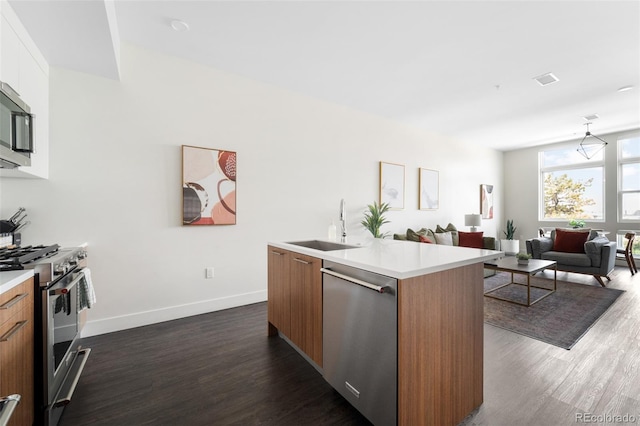 kitchen featuring dark wood-style flooring, a sink, light countertops, appliances with stainless steel finishes, and modern cabinets