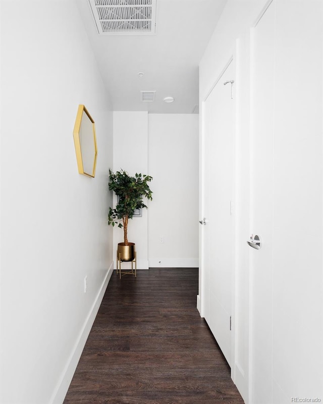 corridor with dark wood-style flooring, visible vents, and baseboards