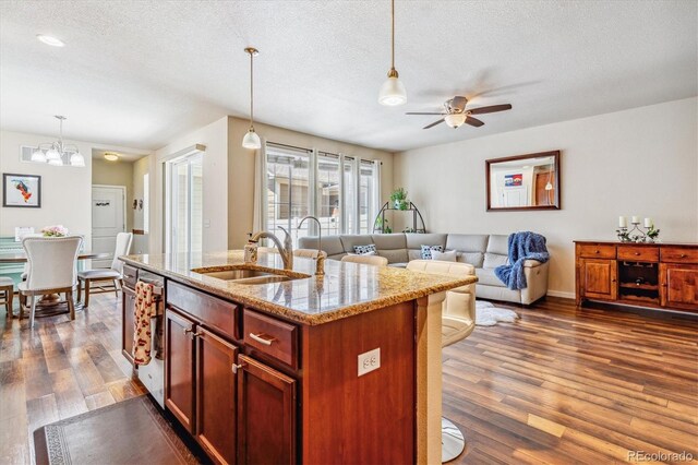 kitchen featuring dark wood-type flooring, a sink, ceiling fan with notable chandelier, and open floor plan
