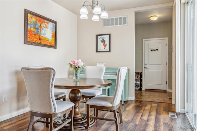 dining area with visible vents, a notable chandelier, and wood finished floors