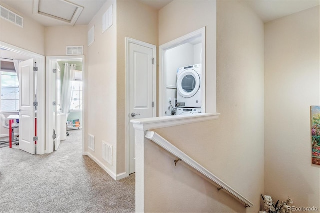 hall with visible vents, stacked washer / dryer, and carpet
