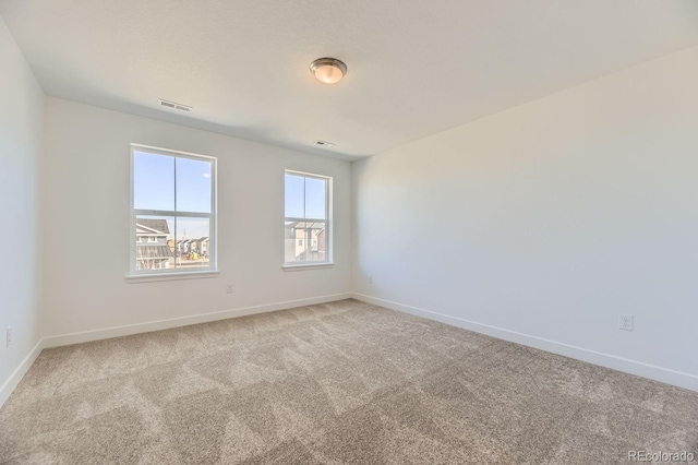 unfurnished room featuring carpet, visible vents, and baseboards