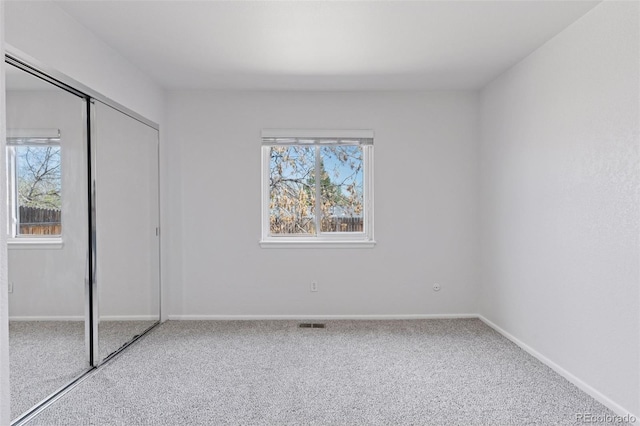 unfurnished bedroom with carpet floors, baseboards, visible vents, and a closet