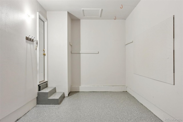 interior space featuring light speckled floor and attic access