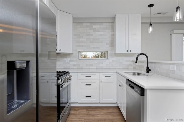 kitchen with hanging light fixtures, white cabinets, sink, backsplash, and stainless steel appliances