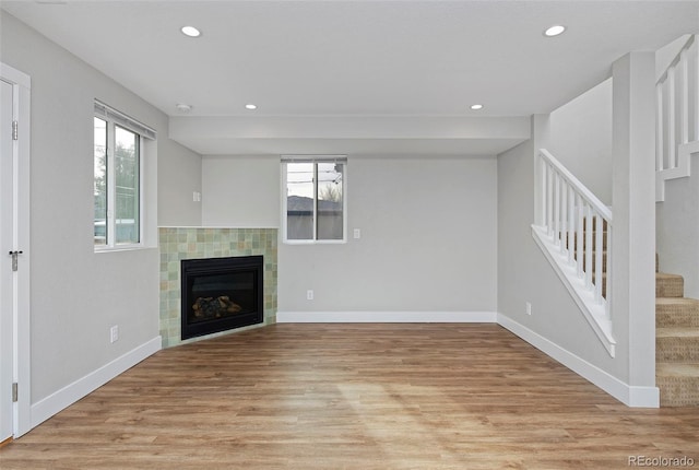 unfurnished living room featuring a tiled fireplace and light wood-type flooring