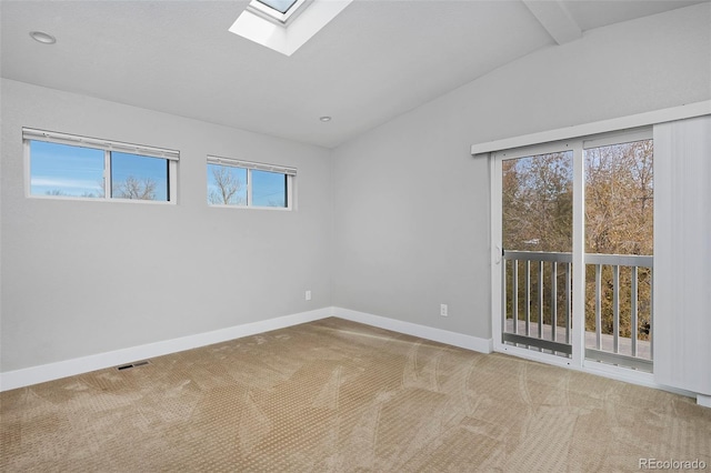 spare room with vaulted ceiling with skylight and carpet