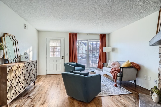 living area featuring a textured ceiling, baseboards, and wood finished floors