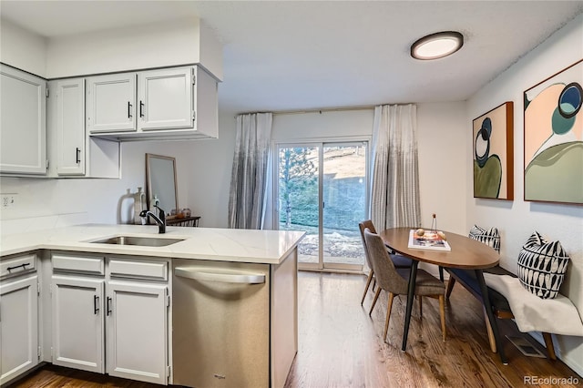 kitchen with sink, dark hardwood / wood-style floors, light stone countertops, stainless steel dishwasher, and kitchen peninsula