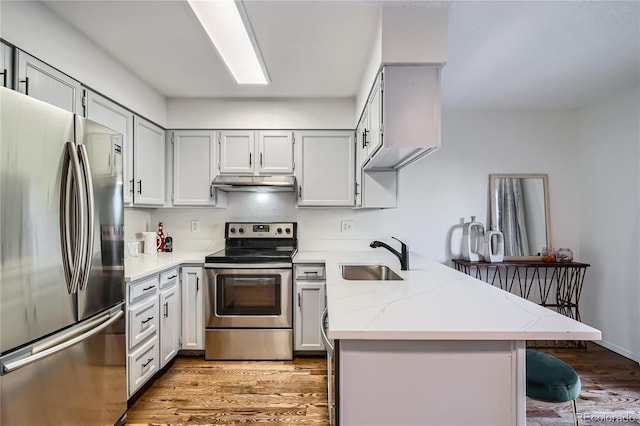 kitchen with stainless steel appliances, a breakfast bar, sink, and kitchen peninsula