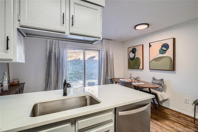 kitchen with stainless steel dishwasher, light wood-style floors, white cabinets, and a sink