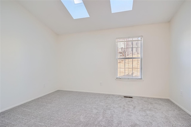 unfurnished room featuring carpet floors, lofted ceiling with skylight, baseboards, and visible vents