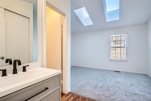 bathroom with lofted ceiling with skylight and vanity