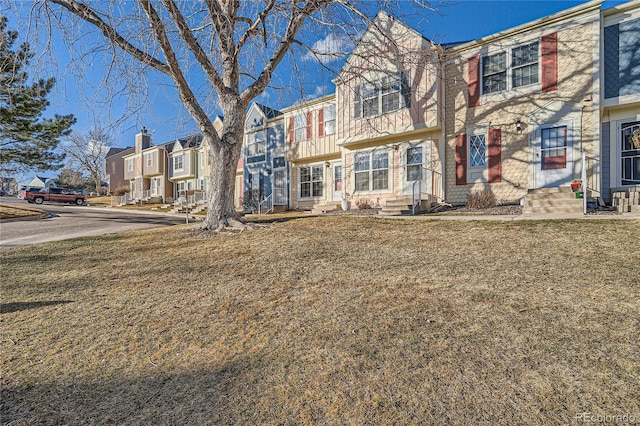 townhome / multi-family property featuring entry steps, a residential view, and a front yard