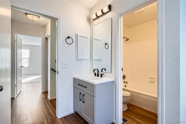 full bath with toilet, shower / bath combination, wood finished floors, and vanity