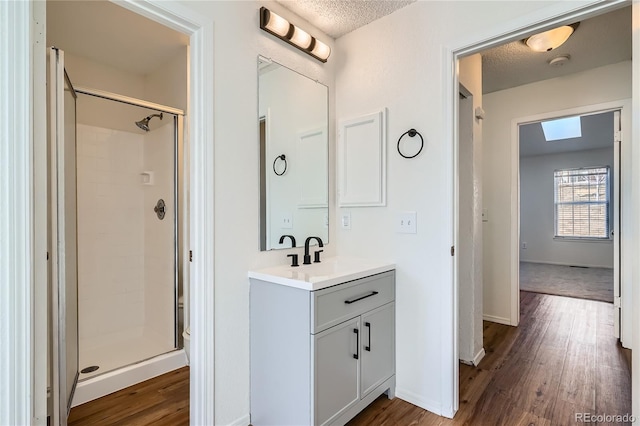 bathroom featuring a shower stall, a textured ceiling, and wood finished floors