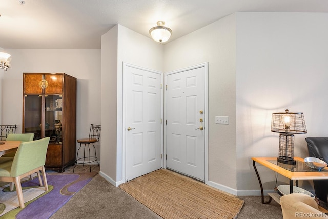 foyer entrance with a chandelier and dark colored carpet