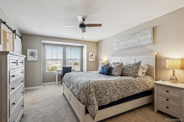 carpeted bedroom featuring a barn door and ceiling fan