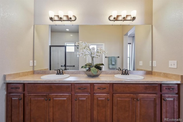 bathroom featuring double vanity, a stall shower, and a sink