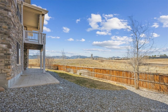 view of yard with a fenced backyard, a mountain view, a patio, and a balcony