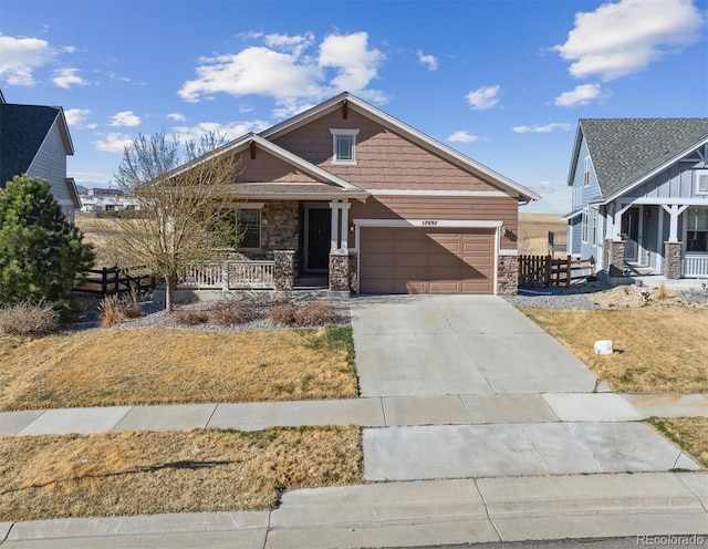 craftsman-style home featuring stone siding, driveway, covered porch, and a garage