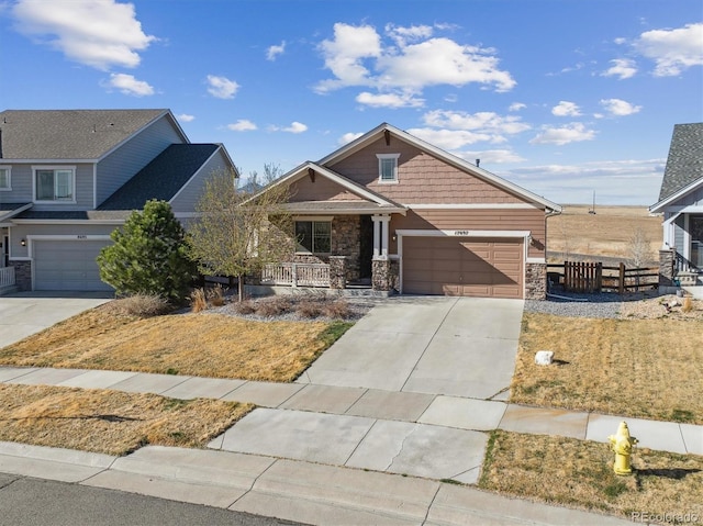 craftsman-style home featuring driveway, a porch, stone siding, fence, and a garage