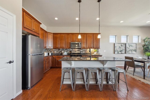 kitchen featuring dark wood finished floors, brown cabinets, appliances with stainless steel finishes, and a sink