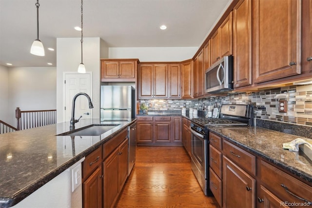 kitchen with dark wood finished floors, backsplash, a sink, brown cabinetry, and appliances with stainless steel finishes