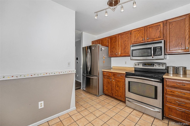 9354 Field Ln, Broomfield, CO 80021 - kitchen with stainless steel appliances, light countertops, light tile patterned floors, and brown cabinets