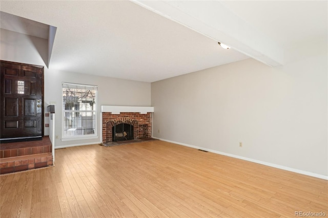 unfurnished living room featuring beamed ceiling, visible vents, baseboards, and hardwood / wood-style floors