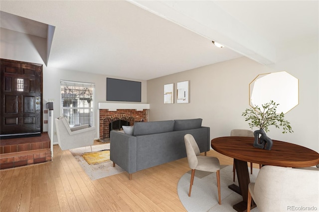 living room with beamed ceiling, light wood-style floors, and a fireplace