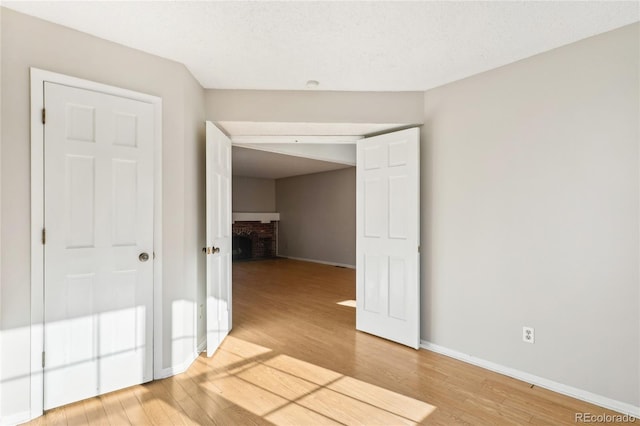 spare room with light wood-type flooring, baseboards, and a fireplace