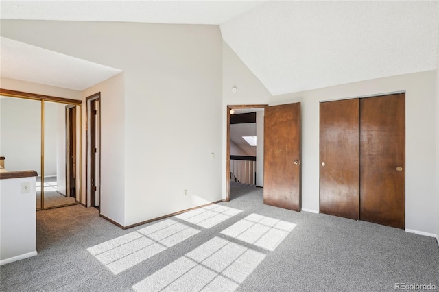 unfurnished bedroom featuring high vaulted ceiling, two closets, baseboards, and carpet floors