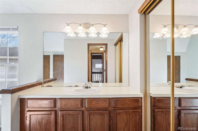 bathroom with a textured ceiling, an inviting chandelier, and vanity