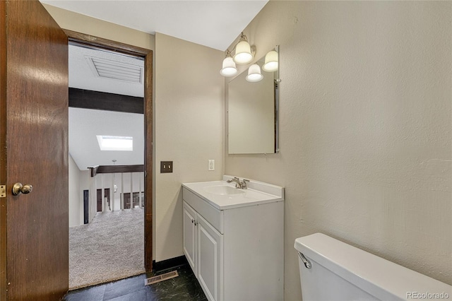 bathroom with visible vents, toilet, lofted ceiling, vanity, and a textured wall