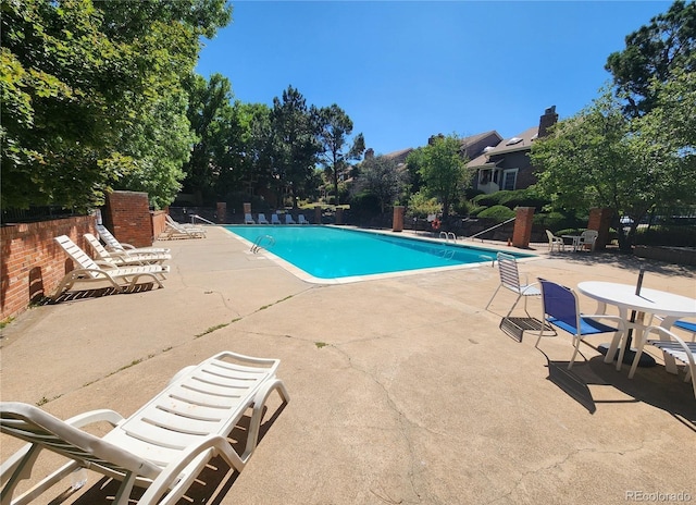 pool with a patio area and fence