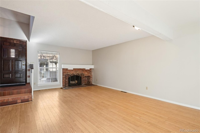 unfurnished living room featuring visible vents, wood finished floors, baseboards, and a fireplace