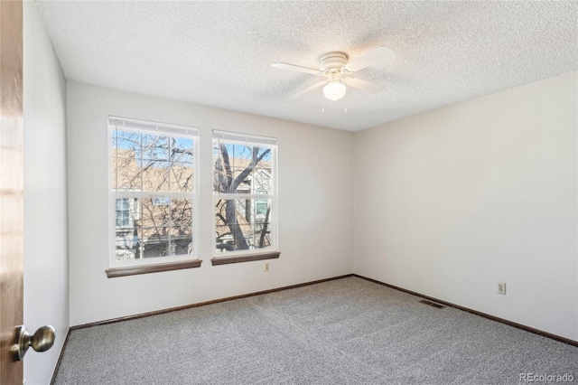 empty room with carpet, a textured ceiling, visible vents, and ceiling fan