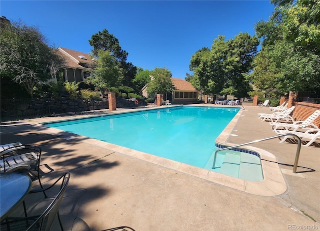pool with a patio area and fence