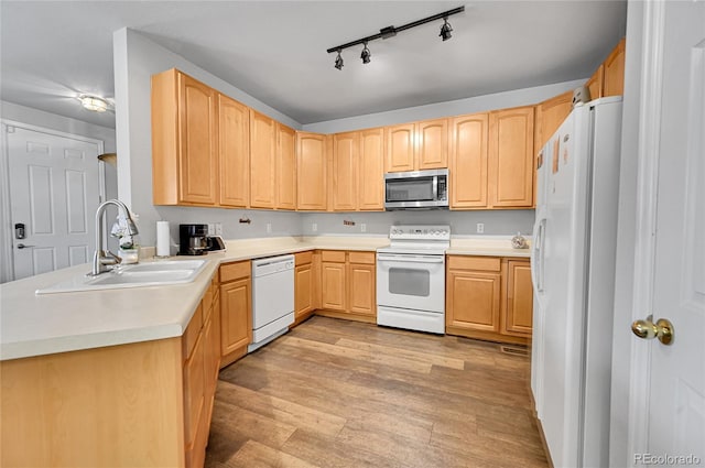 kitchen with white appliances, sink, light wood-type flooring, light brown cabinets, and kitchen peninsula