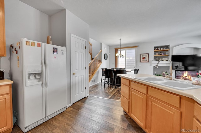 kitchen featuring white refrigerator with ice dispenser, sink, dark hardwood / wood-style flooring, light brown cabinetry, and hanging light fixtures