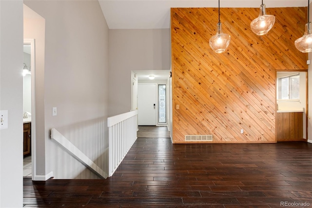 interior space with high vaulted ceiling, wood walls, and dark hardwood / wood-style floors