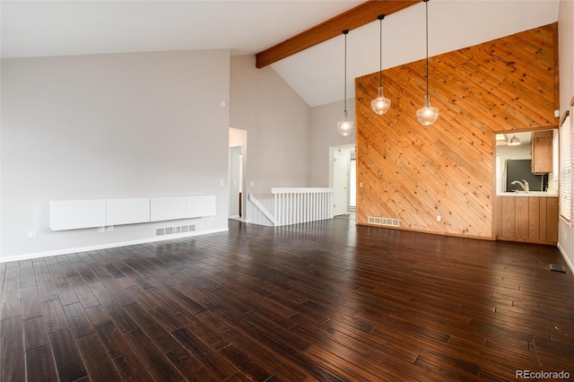 unfurnished living room featuring dark hardwood / wood-style flooring, beamed ceiling, high vaulted ceiling, and wooden walls