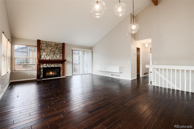 unfurnished living room featuring dark hardwood / wood-style floors, a stone fireplace, and high vaulted ceiling