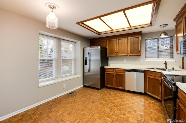 kitchen featuring light parquet floors, pendant lighting, appliances with stainless steel finishes, and sink