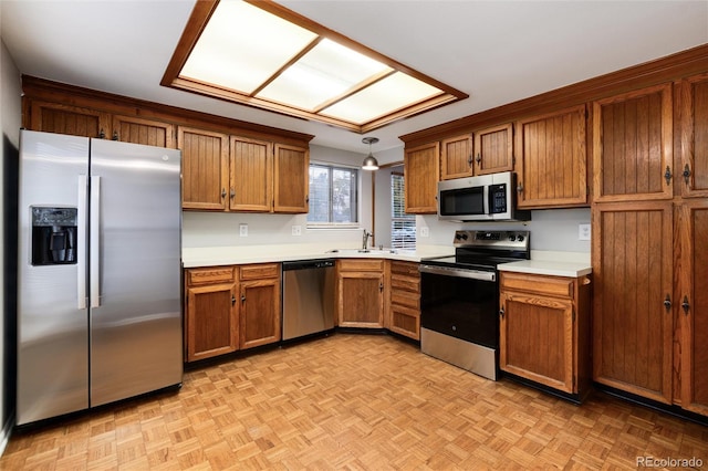 kitchen featuring light parquet floors, hanging light fixtures, sink, and stainless steel appliances