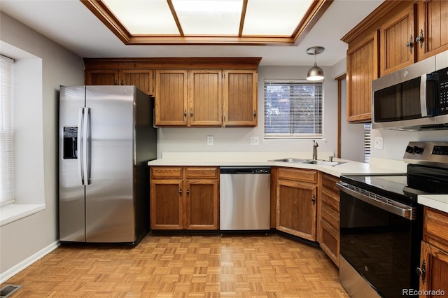 kitchen with stainless steel appliances, hanging light fixtures, sink, and light parquet floors