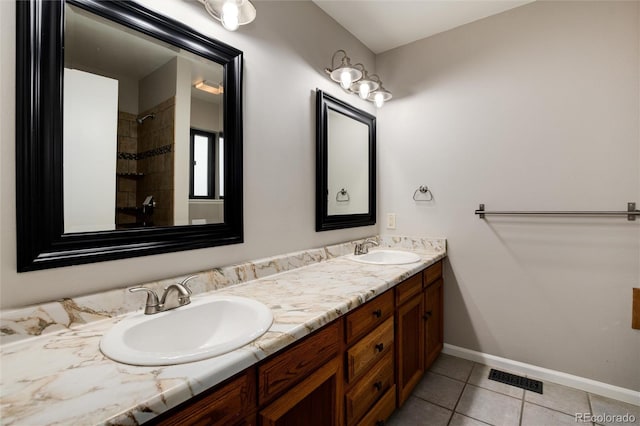 bathroom with tile patterned flooring, vanity, and a tile shower