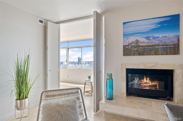 living area with tile patterned flooring, visible vents, and a premium fireplace